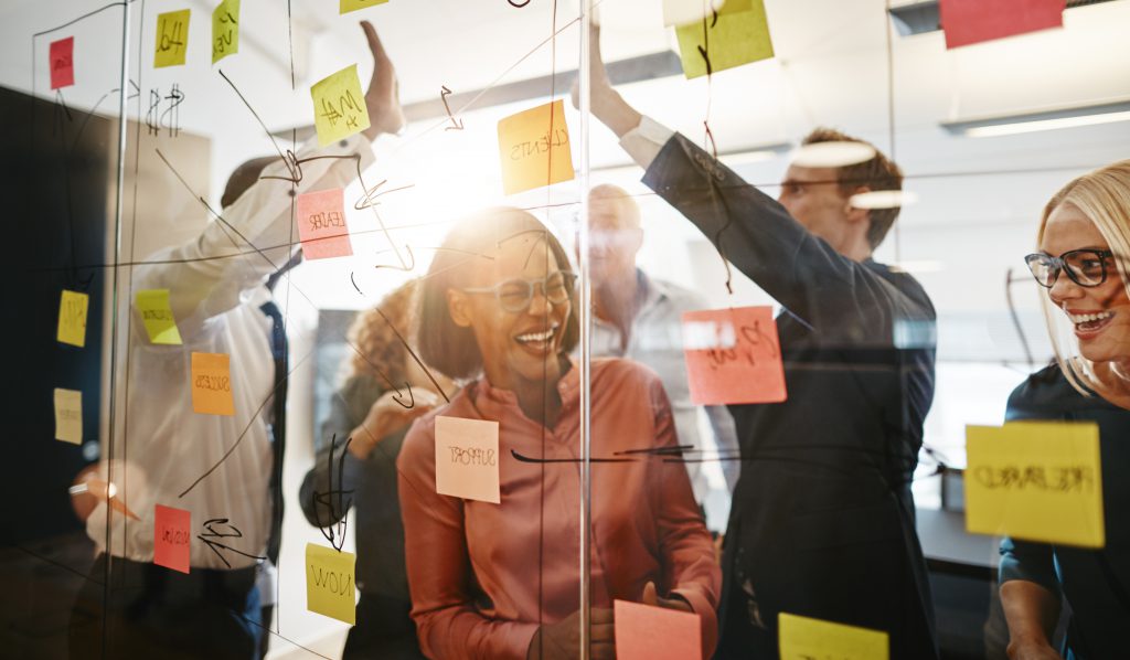 Ecstatic group of businesspeople celebrating together after a brainstorming session Diverse group of ecstatic businesspeople celebrating a winning idea together while brainstorming on a glass wall in a modern office
