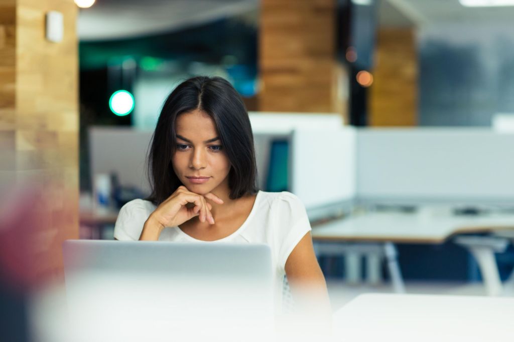 Businesswoman using laptop in office Portrait of a serious businesswoman using laptop in office